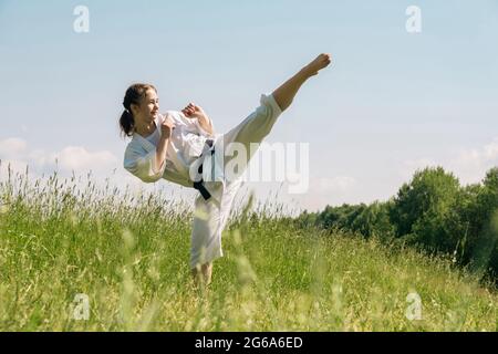 Teen Mädchen üben Karate Kata im Freien, führt die Mawashi geri Kick Stockfoto