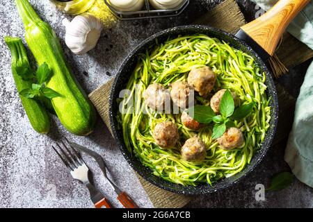 Gesunde Ernährung, Keto-Diät, Mittagessen. Gekochte Zucchini-Nudeln mit Fleischbällchen auf einer steinernen Arbeitsplatte. Draufsicht flach lay Hintergrund. Stockfoto