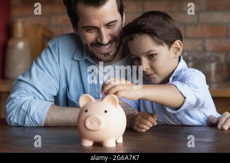 Glücklicher Vater unterrichtet klugen kleinen Sohn, um Geld zu sparen Stockfoto