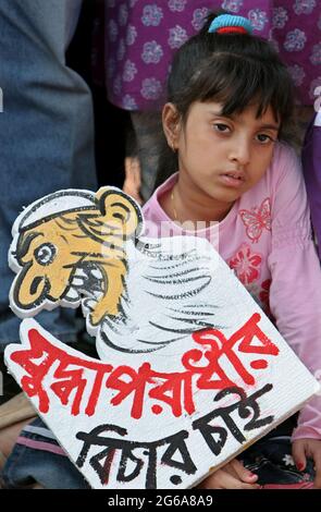 Ein Mädchen, das Plakat hält und bei der Kundgebung des Bijoy Dibosh (Victory Day) 2007 im Kendrio Shahid Minar (Monument für die Märtyrer der Sprachbewegung) in Dhaka, Bangladesch, vor Gericht stellt. Am 16. Dezember 1971 erlangte Bangladesch nach einem neunmonatigen Kampf Unabhängigkeit vom regierenden Westpakistan. Aber auch nach 36 Jahren des Befreiungskrieges sind die Kriegsverbrecher noch nicht vor Gericht gestellt worden. Bangladesch. 16. Dezember 2007. Stockfoto