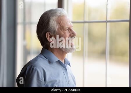 Ein glücklicher, nachdenklicher, älterer Mann aus den 70ern, der aus dem Fenster schaute Stockfoto