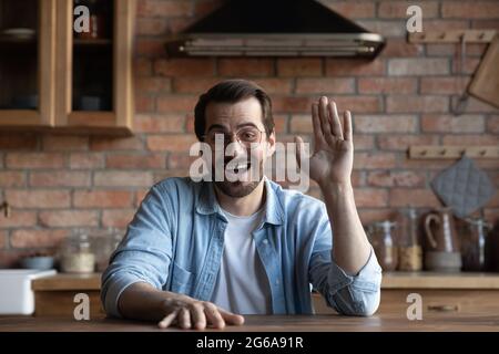 Glücklich aufgeregt junge Millennial Mann trägt Brillen winkende Hand Stockfoto