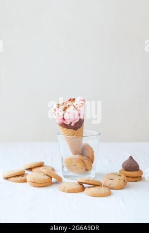 Waffelkegel mit leckerem Eis und Schokoladenkeksen auf dem Tisch. Eiskegel auf dem Glas mit Keksen Stockfoto