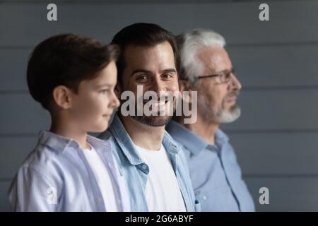 Glücklicher junger Vater, der mit Sohn und Großvater in Reihe steht Stockfoto