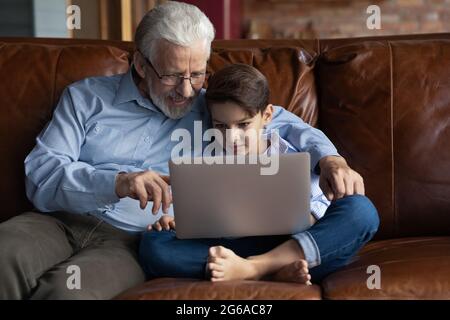 Glücklicher Junge und Opa beim Film auf dem Laptop zu Hause Stockfoto