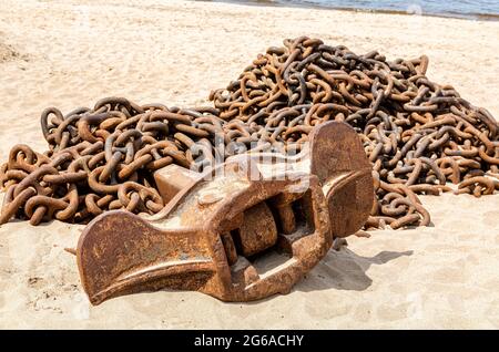 Rostige Ankerkette mit Schiffsanker eines alten Schiffes am Sandstrand Stockfoto