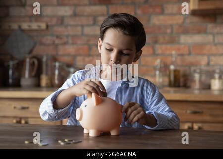 Fokussiertes Schulkind spart Geld beim Kauf Stockfoto