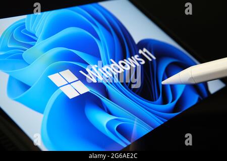 Windows 11-Logo auf dem Bildschirm von Tablet und Benutzer zeigt auf sie mit Stift gesehen. Stafford, Großbritannien, 1. Juli 2021 Stockfoto