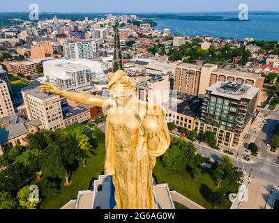 Foto der vorderen Statue auf dem Dach des State Capitol Building in Wisconsin an einem wunderschönen Sommermorgen. Die Spitze der Statue ist die höchste Stockfoto