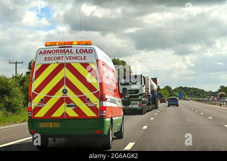 Swindon, England - 2021. Juni: Fahrzeug mit Blinklicht, das eine abnorme Last auf der Autobahn M4 begleitet Stockfoto