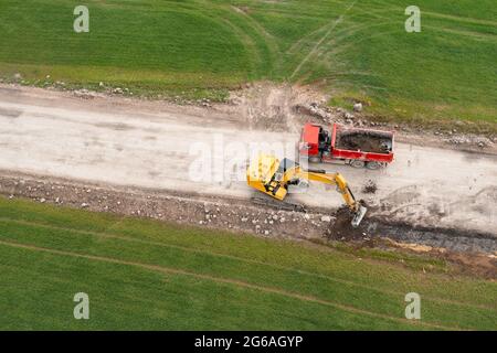 Bagger graben Boden in der Nähe des Feldes und Verladung auf den LKW Stockfoto