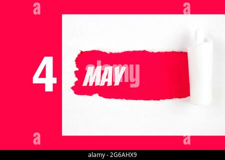 Mai. Tag 4 des Monats, Kalenderdatum. Rotes Loch im weißen Papier mit abgerissenen Seiten mit Kalenderdatum. Frühling Monat, Tag des Jahres Konzept Stockfoto