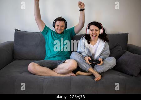 Paar spielen Videospiele zusammen sitzen auf dem Sofa Couch Stockfoto