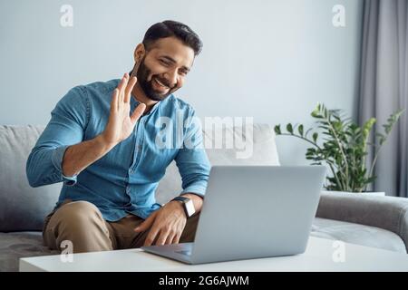 Indischer Geschäftsmann winkt Hand zu Online-Client mit Laptop-Computer Stockfoto