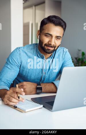 Indischer Mann mit Laptop und Kopfhörer für Online-Lernen und E-Learning Stockfoto