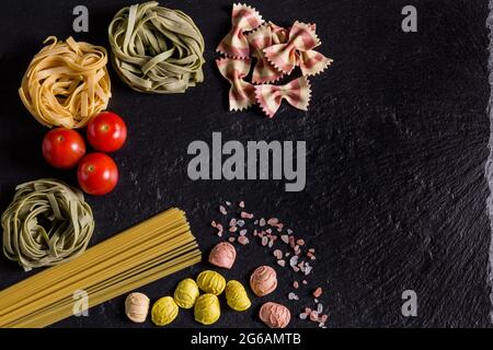 Grüne und gelbe Tagliatelle, Spaghetti und Pasta-Schmetterlinge, Salz und Tomaten Stockfoto