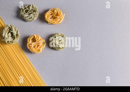 Spaghetti und grüne und gelbe Tagliatelle auf hellem Hintergrund Stockfoto