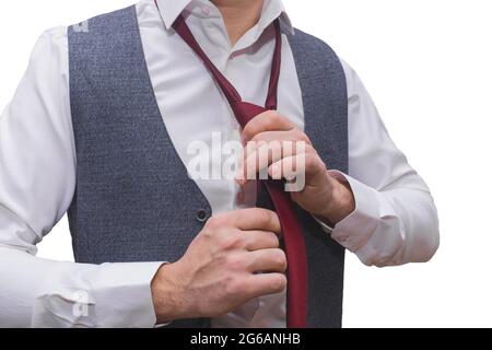 Die Hände des Mannes sind in einem weißen Hemd und einer grauen Weste mit einer roten Krawatte in Nahaufnahme gehalten. Stockfoto