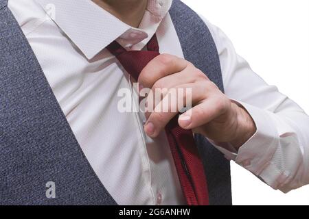 Die Hände des Mannes sind in einem weißen Hemd und einer grauen Weste mit einer roten Krawatte in Nahaufnahme gehalten. Stockfoto