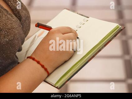 Die Hand des Mädchens hält einen Stift und schreibt in einem Notizbuch Platz für Text und Design Nahaufnahme. Stockfoto