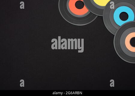 Mehrfarbige 7-Zoll-Single-Vinyl-Schallplatten auf schwarzem Hintergrund mit leerem Platz für Text. Ansicht von oben nach unten flach liegend mit horizontaler Ausrichtung Stockfoto