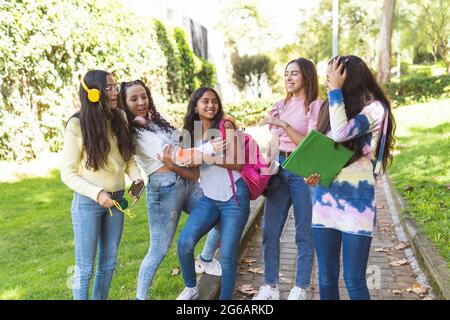 Eine Gruppe von fünf Teenagern aus Latina, die auf dem Weg zur High School fröhlich lachen Stockfoto