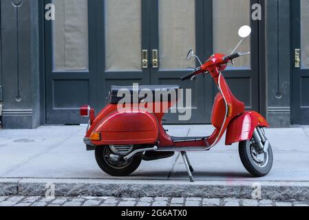 Kleines, rotes Motorrad, das auf einer Straße in New York City geparkt ist. Stockfoto