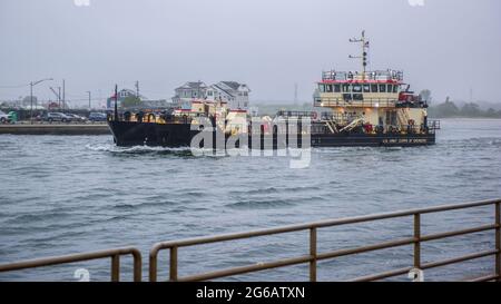 DAS US Army Corps of Engineers barge, das an einem bewölkten Tag aus dem Bay Outlet Manasquan, NJ, auf See fährt. Stockfoto