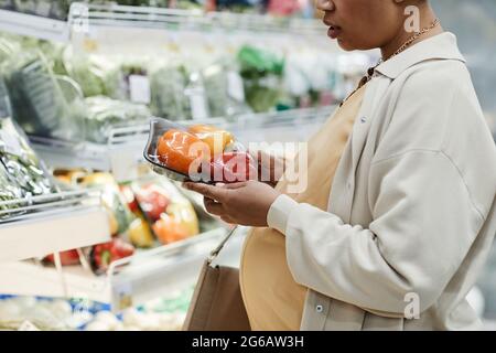 Verkürzte Seitenansicht Porträt einer schwanger afroamerikanischen Frau, die beim Einkaufen im Supermarkt Lebensmittel kauft Stockfoto