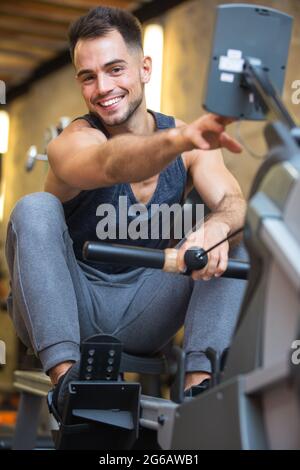 Glücklicher Mann beim Training auf dem Rudergerät Stockfoto