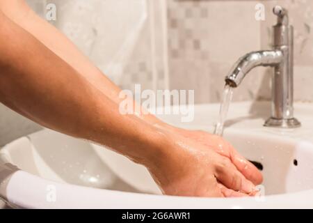 Nahaufnahme eines Mannes, der seine Hände im Badezimmer wascht. Hygienekonzept zur Prävention COVID - 19. Stockfoto
