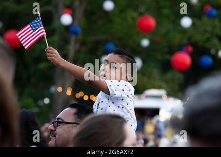 Washington, Usa. Juli 2021. Gilbert Rodriguez, sechs Jahre alt, aus Long Beach, Kalifornien, hält die US-Nationalflagge auf den Schultern seines Vaters Eddie Rodriguez, während US-Präsident Joe Biden während einer Feier des Unabhängigkeitstages in Washington, DC, USA, am 04. Juli 2021 auf dem South Lawn des Weißen Hauses eine Rede hält. Quelle: SIPA USA/Alamy Live News Stockfoto