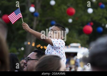Gilbert Rodriguez, sechs Jahre alt, aus Long Beach, Kalifornien, hält die US-Nationalflagge auf den Schultern seines Vaters Eddie Rodriguez, während US-Präsident Joe Biden während einer Feier des Unabhängigkeitstages in Washington, DC, USA, am 04. Juli 2021 auf dem South Lawn des Weißen Hauses eine Rede hält. Stockfoto