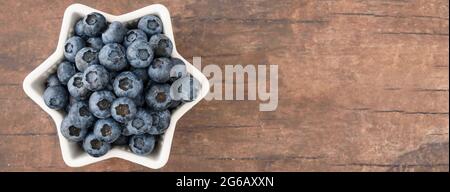Heidelbeeren für den 4. Juli, Heidelbeeren in sternförmigen Schale, vor einem hölzernen Hintergrund Stockfoto