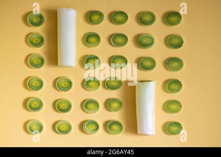 Lauch-Scheiben, die auf einem gelben Hintergrund in Reihen angeordnet sind Stockfoto
