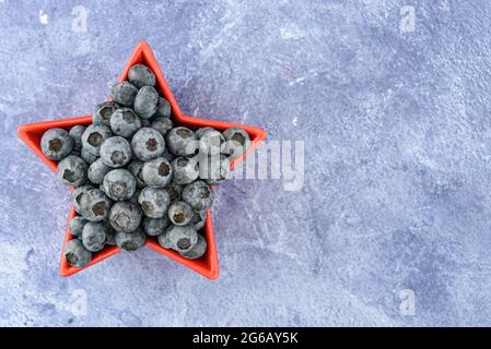 Heidelbeeren für den 4. Juli, Heidelbeeren in sternförmiger Schale, auf blauem Hintergrund Stockfoto