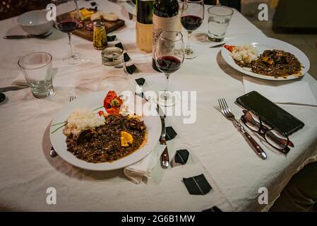 Typisch brasilianisches Gericht namens Feijoada. Hergestellt aus schwarzen Bohnen, Schweinefleisch und Wurst. Serviert auf einem weißen Teller während eines Meetings. Stockfoto