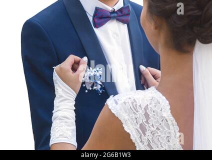 Die Umarmung der Braut und des Bräutigams bei der Hochzeit. Ein Mann in einem blauen Anzug und weißem Hemd, mit einem Schmetterling umarmt ein Mädchen in einem weißen Kleid. Stockfoto