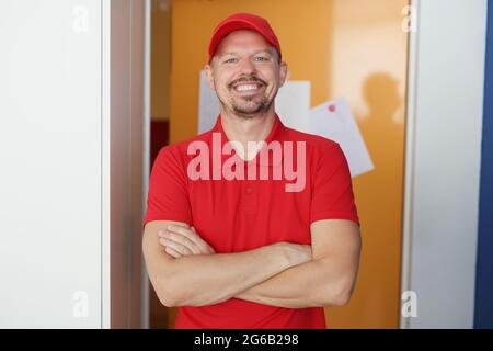 Porträt eines lächelnden männlichen Kuriers in roter Uniform Stockfoto