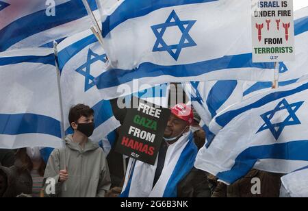 London, Großbritannien. Mai 2021. Pro-israelische Anhänger schwingen während des Protestes Fahnen, halten Plakate fest.Pro-israelische Demonstranten demonstrieren vor der israelischen Botschaft in der High Street Kensington, um den am 21. Mai vereinbarten Waffenstillstand zu unterstützen. Eine kleine Gruppe von Palästinensern kam zur Gegendemonstration der israelischen Demonstration, doch die Polizei bildete eine Absperrung zwischen den beiden Massen, um jegliche Gewalt zu vermeiden. (Foto von Martin Pope/ SOPA Images/Sipa USA) Quelle: SIPA USA/Alamy Live News Stockfoto