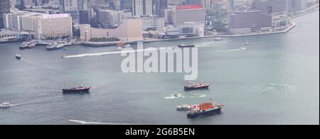 Eine Reihe von Booten mit chinesischen und Hongkonger Flaggen segeln am 1. Juli – dem Tag der Gründung der Sonderverwaltungsregion Hongkong – durch den Hafen von Victoria. Stockfoto