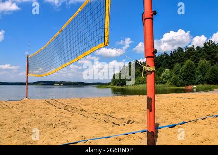 Beachvolleyballplatz neben dem See und Wald an einem sonnigen Tag Stockfoto