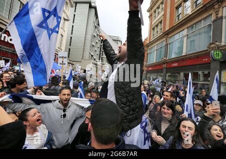 London, Großbritannien. Mai 2021. Ein Protestler auf den Schultern eines Freundes singt und schwenkt während des Protestes eine israelische Flagge.Pro-israelische Demonstranten versammeln sich vor der israelischen Botschaft in der High Street Kensington, um den am 21. Mai vereinbarten Waffenstillstand zu unterstützen. Eine kleine Gruppe von Palästinensern kam zur Gegendemonstration der israelischen Demonstration, doch die Polizei bildete eine Absperrung zwischen den beiden Massen, um jegliche Gewalt zu vermeiden. Quelle: Martin Pope/SOPA Images/ZUMA Wire/Alamy Live News Stockfoto