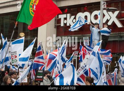 London, Großbritannien. Mai 2021. Zwei Demonstranten sahen während des Protestes auf einem Laternenpfahl über einem Meer von Flaggen protestieren.Pro-israelische Demonstranten versammelten sich vor der israelischen Botschaft in der High Street Kensington, um den am 21. Mai vereinbarten Waffenstillstand zu unterstützen. Eine kleine Gruppe von Palästinensern kam zur Gegendemonstration der israelischen Demonstration, doch die Polizei bildete eine Absperrung zwischen den beiden Massen, um jegliche Gewalt zu vermeiden. Quelle: Martin Pope/SOPA Images/ZUMA Wire/Alamy Live News Stockfoto