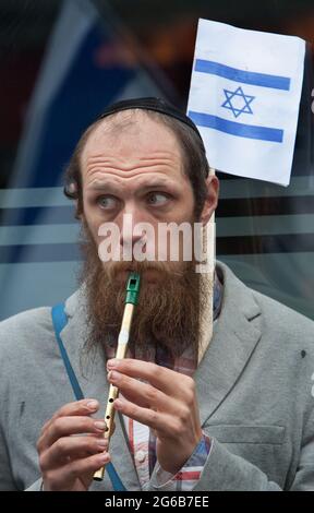 London, Großbritannien. Mai 2021. Ein Protestler mit israelischer Flagge spielt während des Protestes eine Flöte. Pro-israelische Demonstranten demonstrieren vor der israelischen Botschaft in der High Street Kensington, um den am 21. Mai vereinbarten Waffenstillstand zu unterstützen. Eine kleine Gruppe von Palästinensern kam zur Gegendemonstration der israelischen Demonstration, doch die Polizei bildete eine Absperrung zwischen den beiden Massen, um jegliche Gewalt zu vermeiden. Quelle: Martin Pope/SOPA Images/ZUMA Wire/Alamy Live News Stockfoto