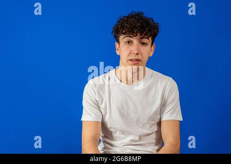 Porträt EINES ernsthaften jungen Mannes auf blauem Hintergrund. Posing-Konzept Stockfoto