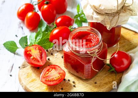 Tomatenmark, Haushaltung. Tomatensauce aus reifen Tomaten auf einer Holzplatte. Stockfoto