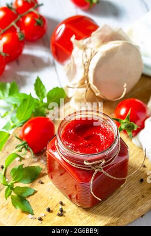 Tomatenmark, Haushaltung. Tomatensauce aus reifen Tomaten auf einer Holzplatte. Stockfoto