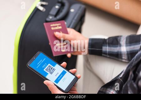 Impfpass, Reisender Mann mit Gesundheitspass der Impfpass-Zertifizierung auf Smartphone-App am Flughafen vor dem Einsteigen in das Flugzeug während der coro Stockfoto