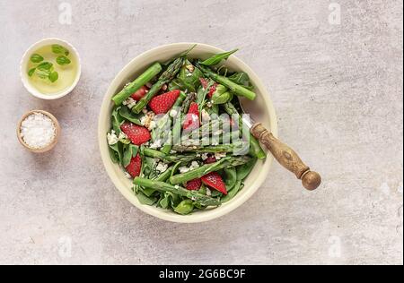 Salat aus Erdbeere, Spinat, grünem Spargel, Rucola und Feta-Käse. Stockfoto